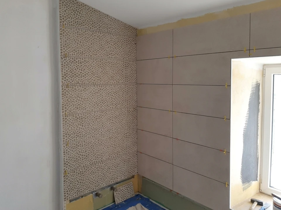 Chantier de pose de carrelage mural en cours, intérieur de pièce rénovée