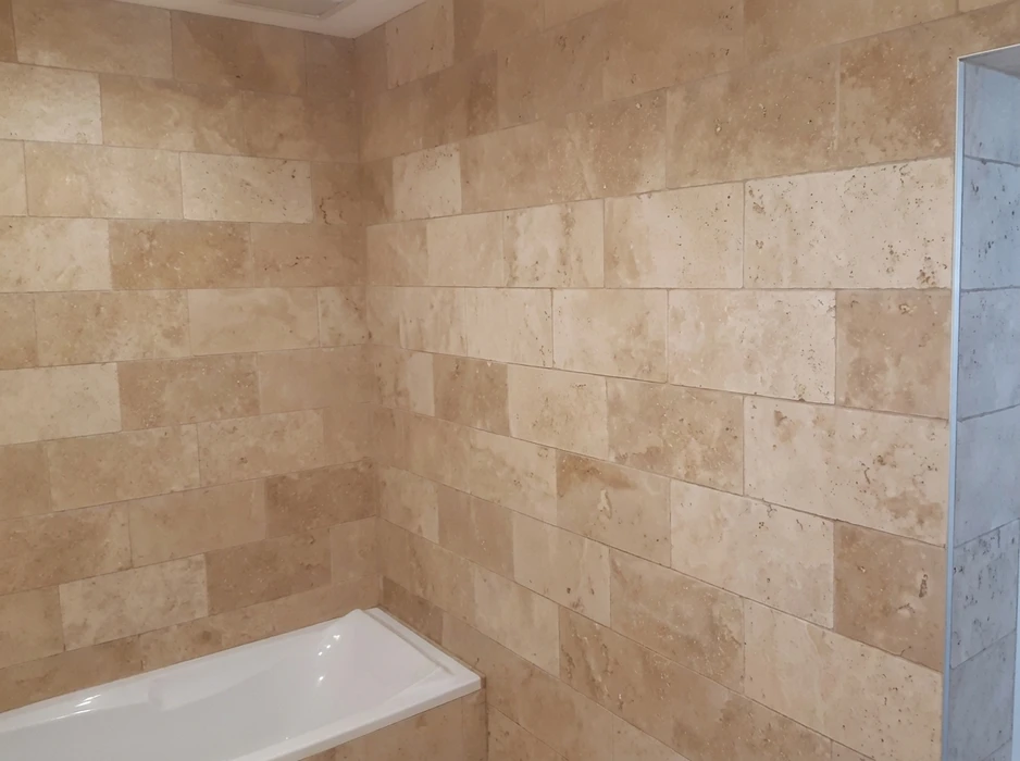 Salle de bain carrelée en pierre naturelle travertin beige, posée en appareillage décalé (brick pattern)